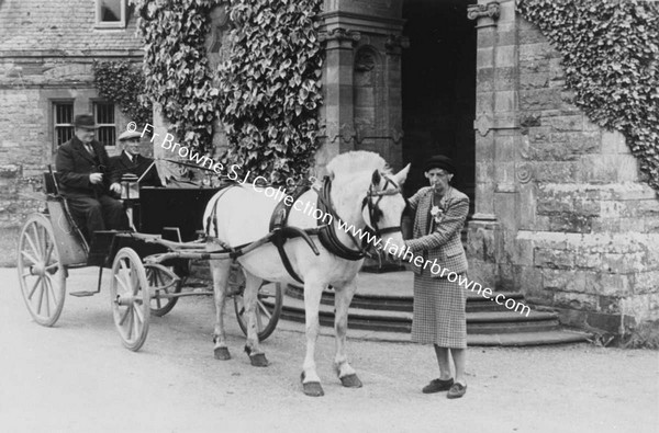 WOMAN HOLDING HORSE AND CARRIAGE WITH TWO MEN IN CARRIAGE